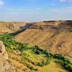 Info Shymkent - The Mashat canyon forms with trees and meadows on the floor of the canyon a green line through rocky terrain